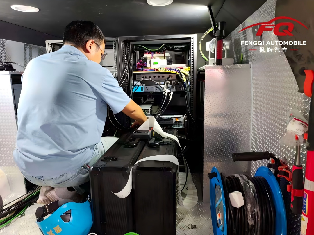 A Fengqi technician working on the electrical integration of the command vehicle — adapting 110V/60Hz and 220V/50Hz systems side by side.
